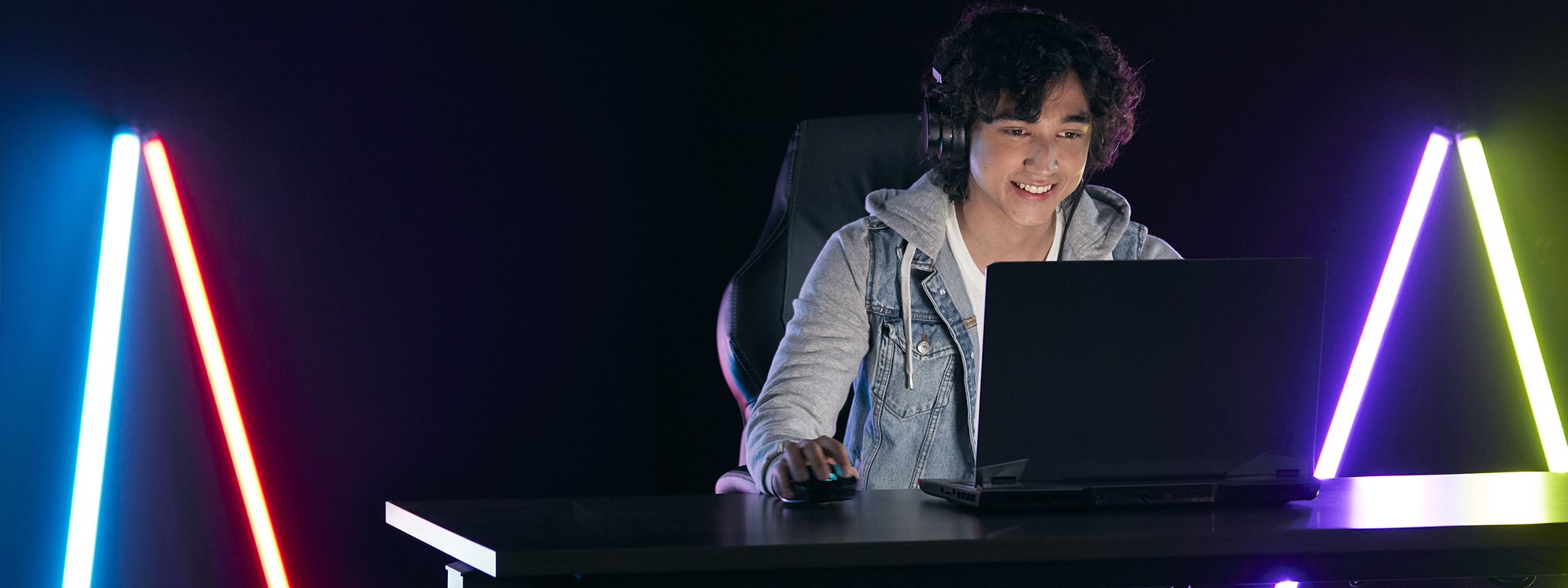 Ein junger Gamer, der in einem dunklen Raum an seinem Laptop spielt