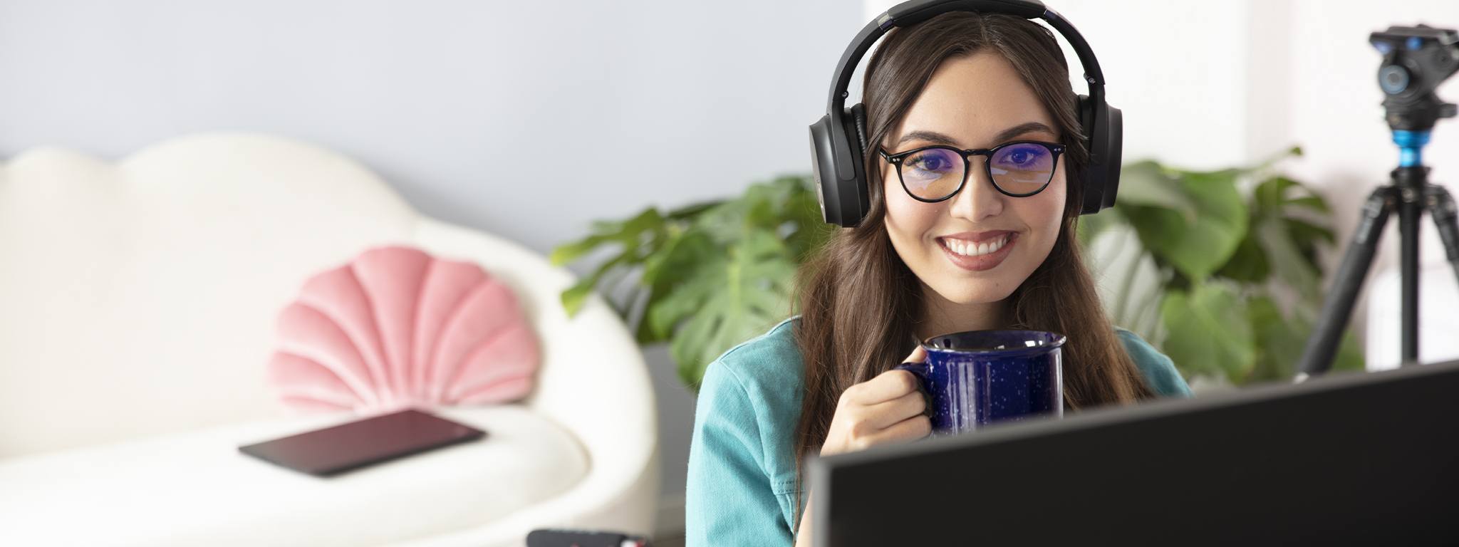 Immagine di una ragazza che tiene in mano una tazza blu mentre guarda al suo monitor nell’ufficio di casa