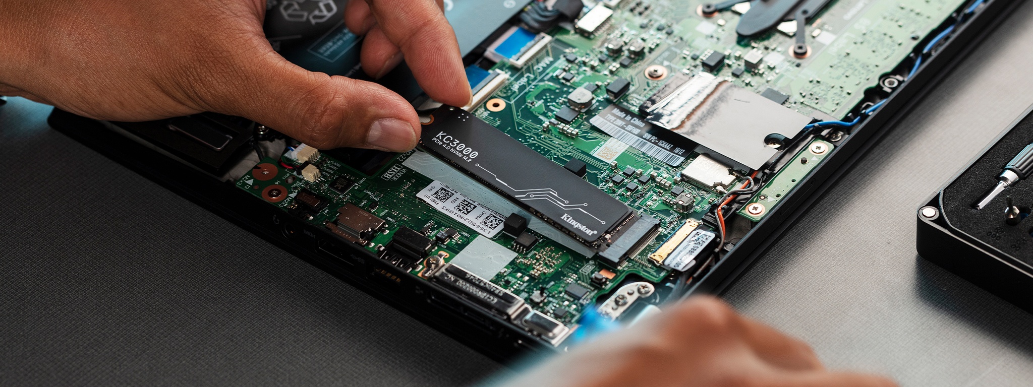 A hand installing KC3000 SSD into a laptop