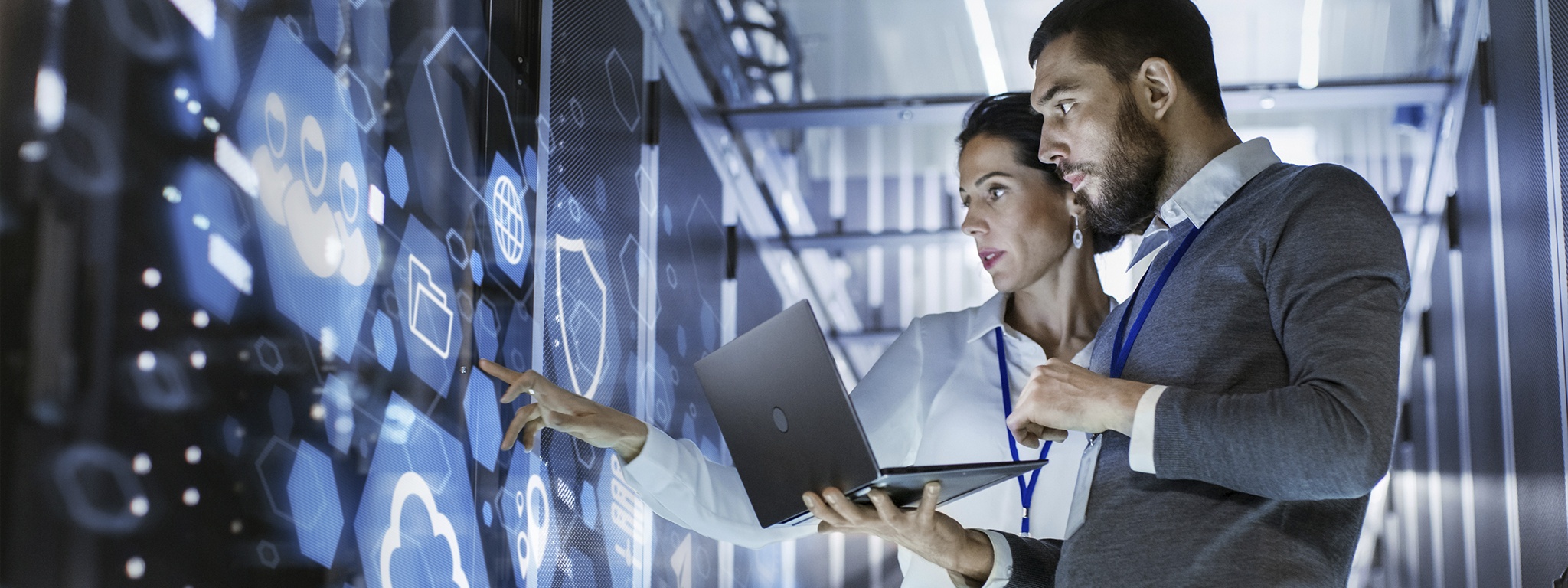 Immagine di uno specialista IT che tiene in mano un laptop mentre parla con un tecnico server in una sala server di un data center