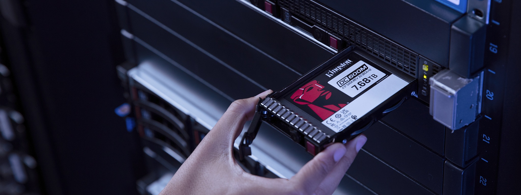 一隻手將 Kingston DC600M SSD 固態硬碟安裝到伺服器機架中