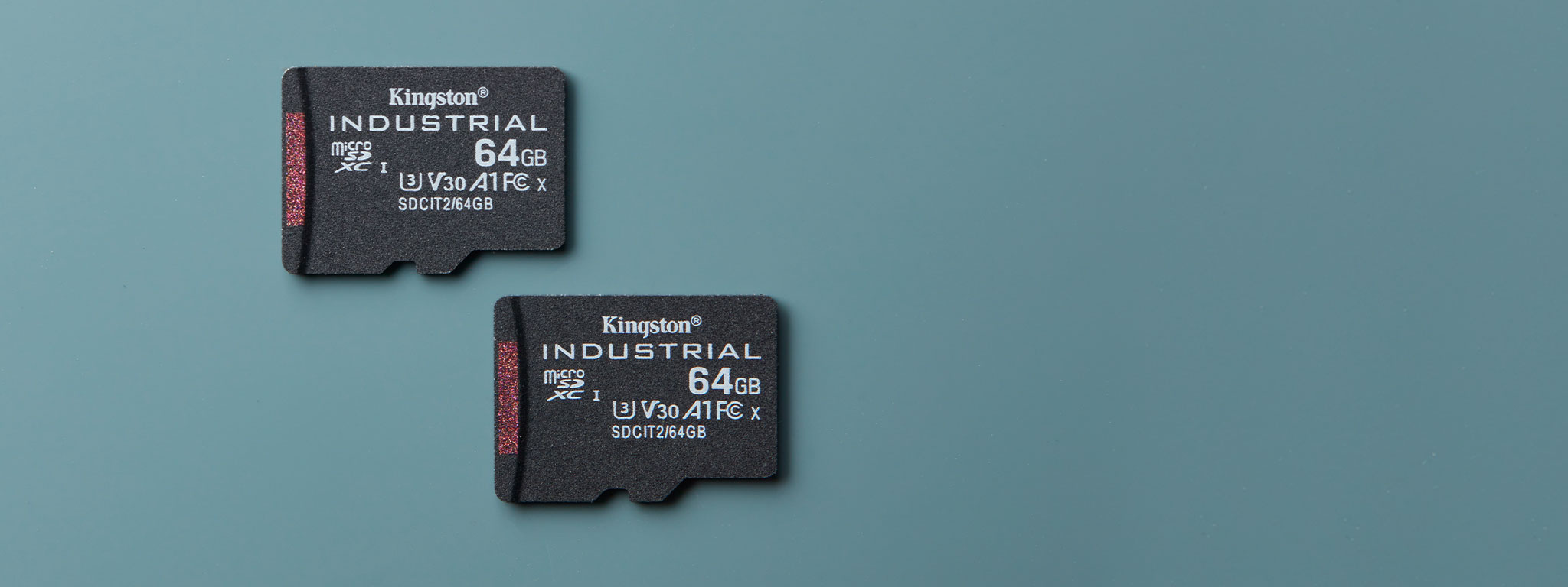 Una coppia di schede Industrial microSD, entrambe con capacità di 64GB, su una superficie blu-verde