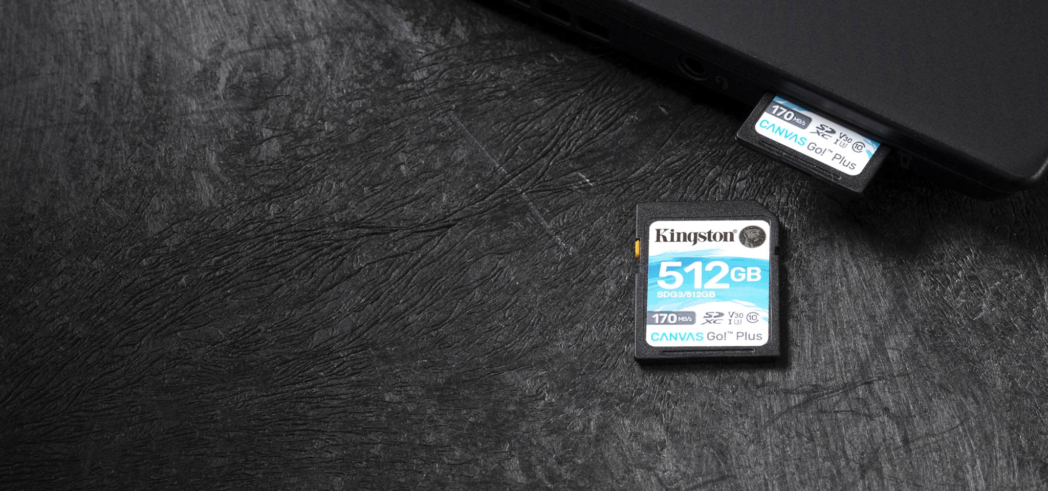 Kartu microSD Canvas Go! Plus diletakkan pada permukaan hitam dan di belakangnya ada kartu lain yang dipasang ke laptop