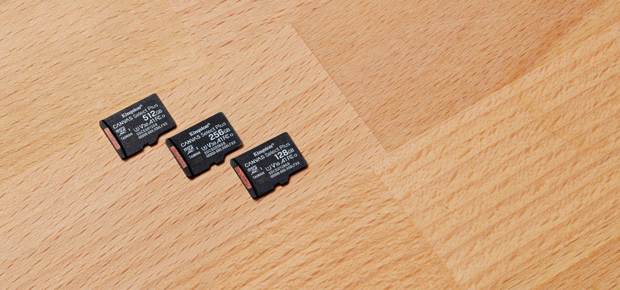 Três cartões microSD Canvas Select Plus, cada um com uma capacidade diferente, em uma mesa de madeira