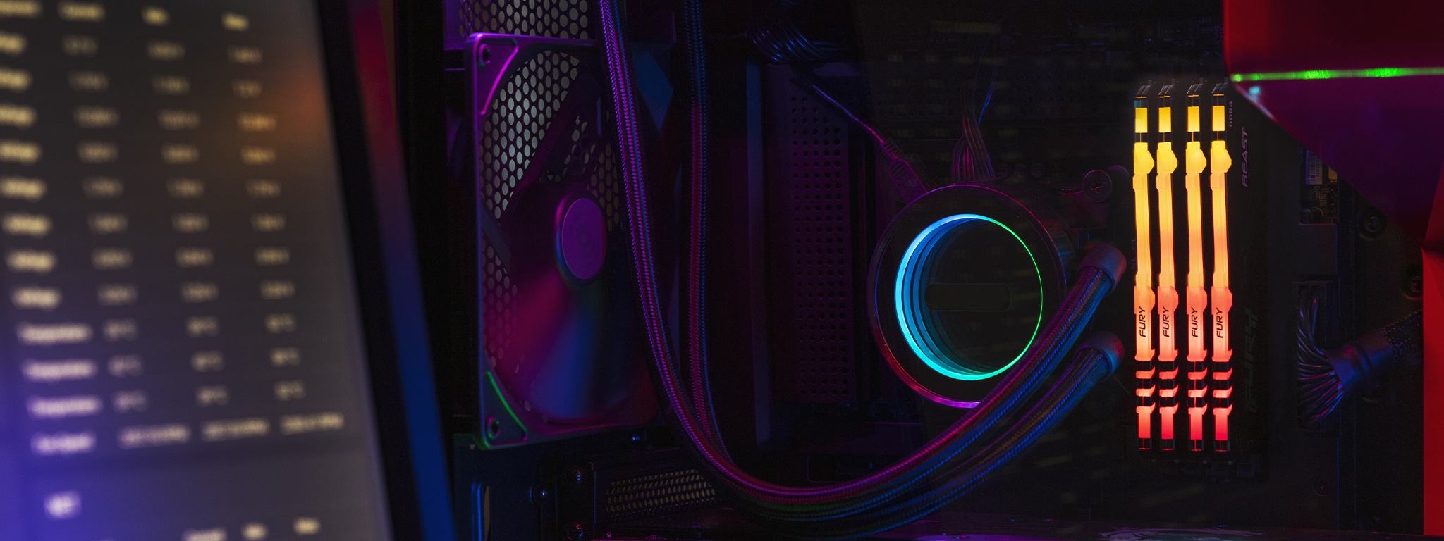 CPU 冷却ファンや配線と一緒にマザーボードに接続された Kingston FURY Beast RGB と、左側で PC の仕様を映すモニタ