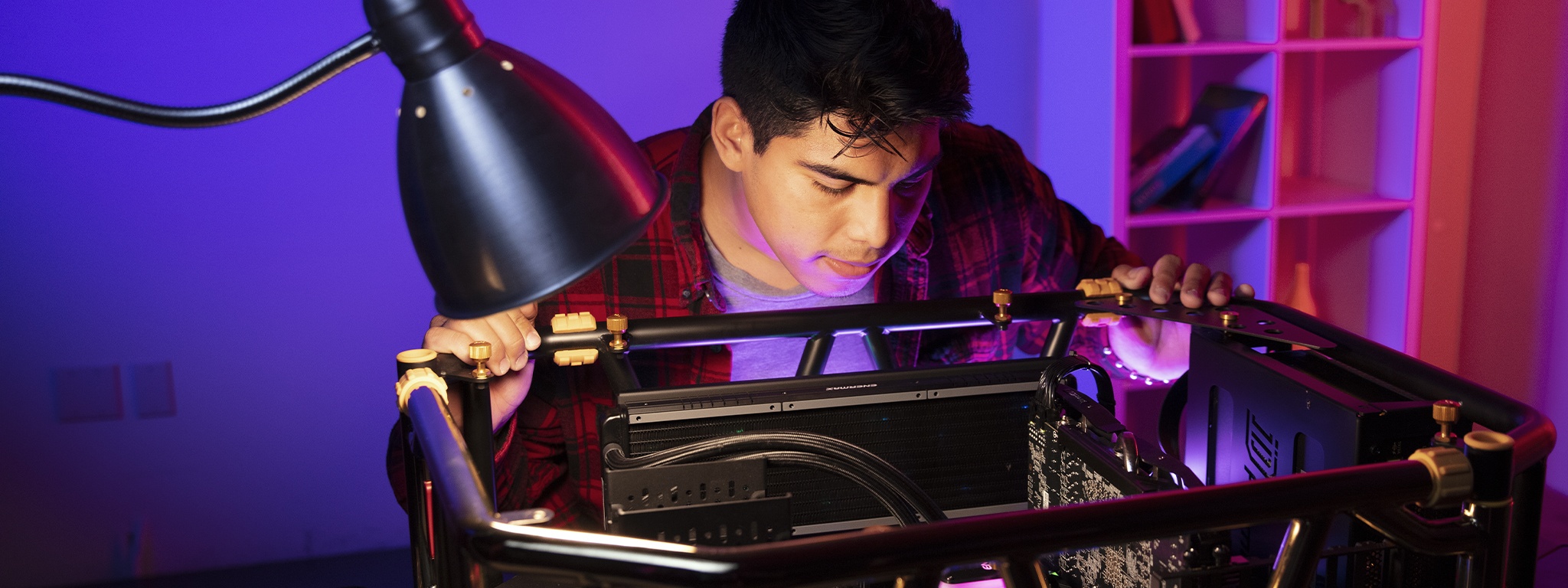 a young man looking into his open desktop computer case on a desk to build a new gaming PC