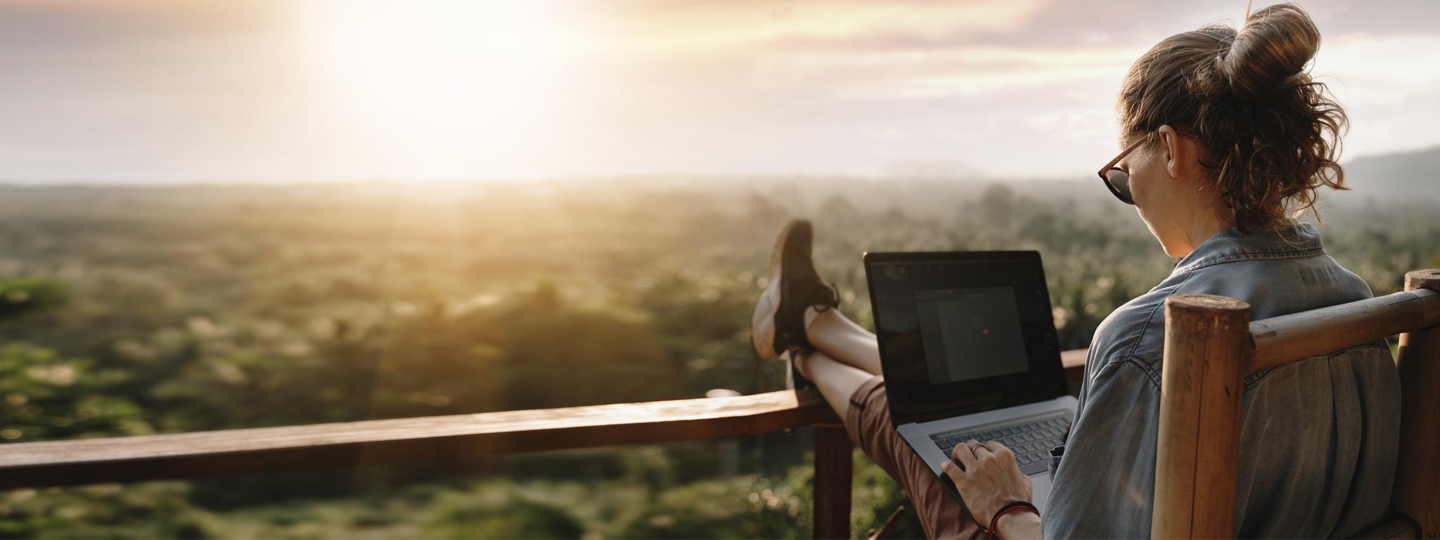 uma moça trabalhando em um laptop ao por do sol na varanda (a girl working on a laptop in the sunset on the balcony)