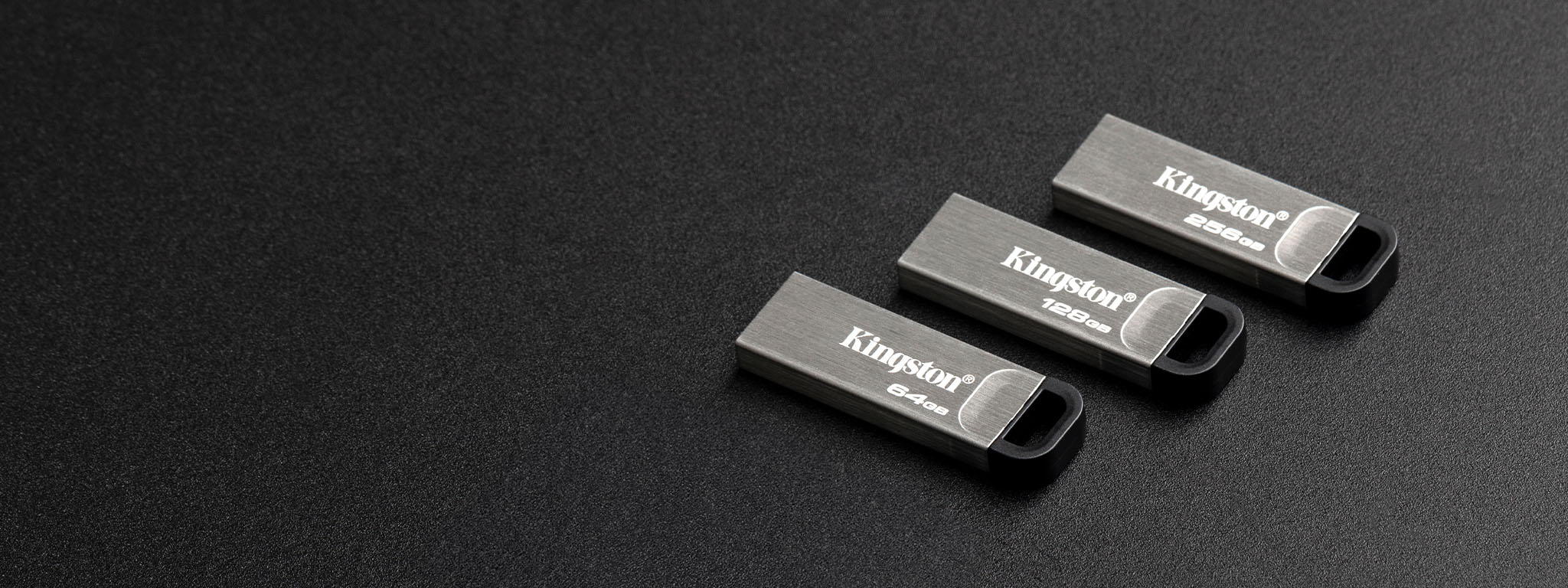 Pandangan atas pada empat flash disk USB DT Kyson dengan kapasitas berbeda yang diletakkan pada permukaan hitam