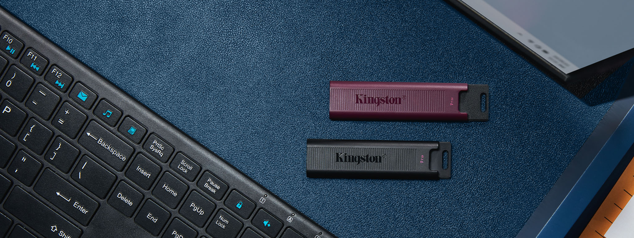 Overhead view of DT Max flash drives, USB-C in black and USB-A in burgundy, sitting between a keyboard and monitor
