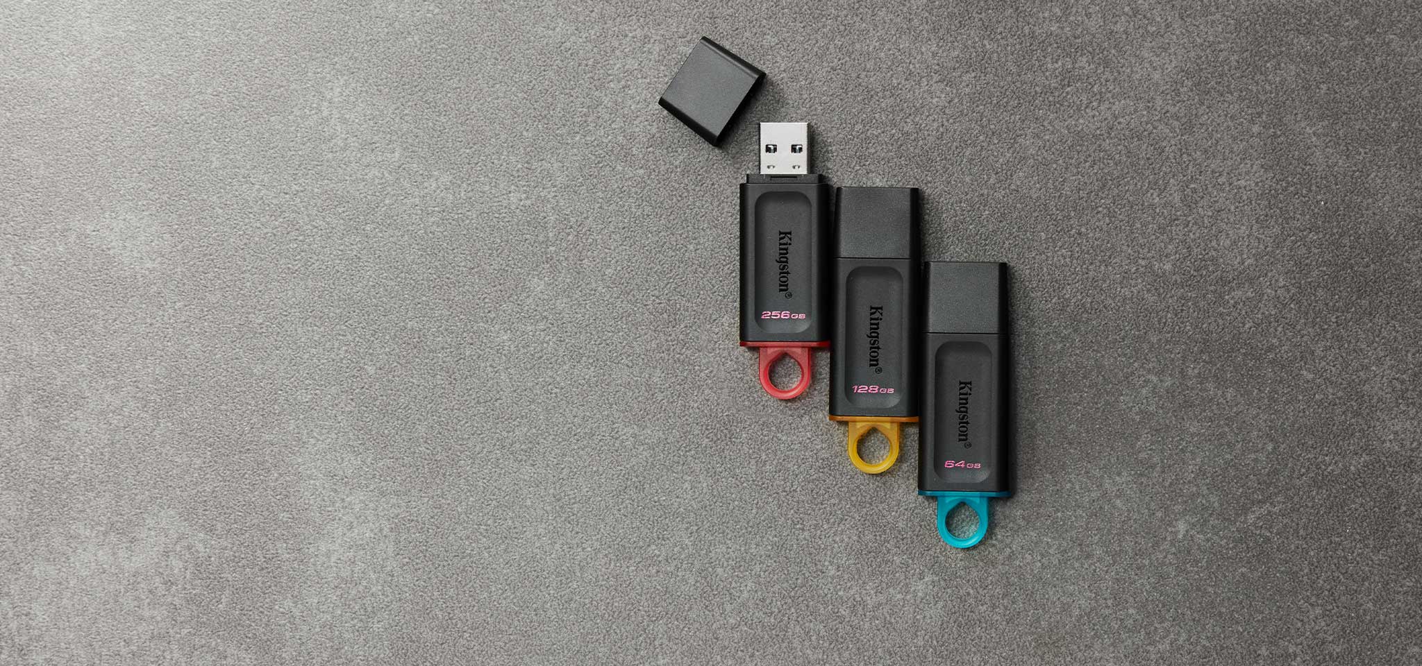 グレーのカーペットの上に、容量ごとにさまざまな色の 4 つの異なる DT Exodia USB フラッシュドライブを上から見下ろした図