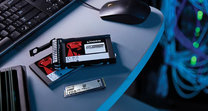 Sepasang SSD Kingston 2,5" dan satu SSD M.2 yang ditaruh di atas meja di sebelah keyboard dan mouse.