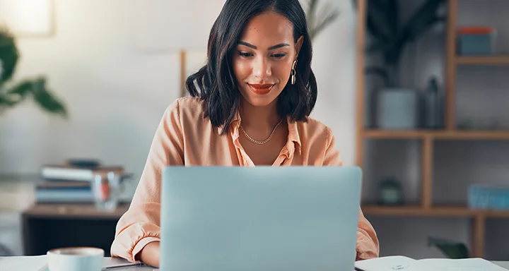 Uma mulher sentada à mesa usando um laptop.