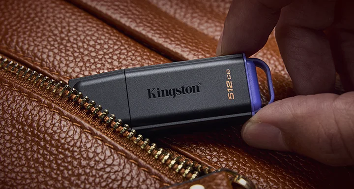 A DataTraveler Exodia USB flash drive in a pocket of a brown leather bag.