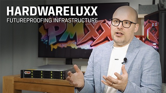 Dennis Bode podczas wywiadu w biurze; w tle szafa serwerowa i monitor z logo PMXX