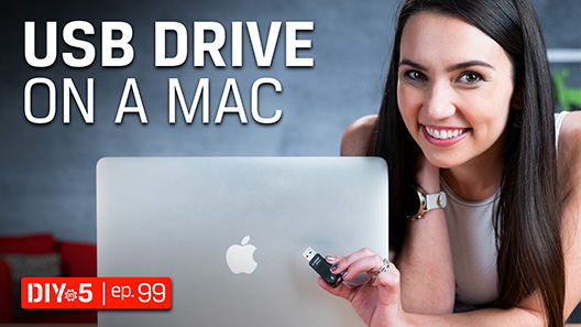 Trisha holding a USB drive in front of a MacBook Pro