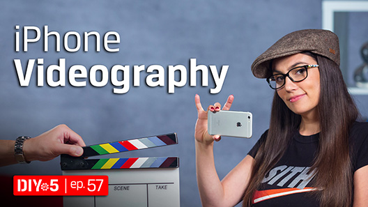 A hand holds a clapboard in front of Trisha as she wears a beret and shoots with an iPhone.